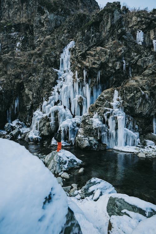 Person Standing near Frozen Waterfall