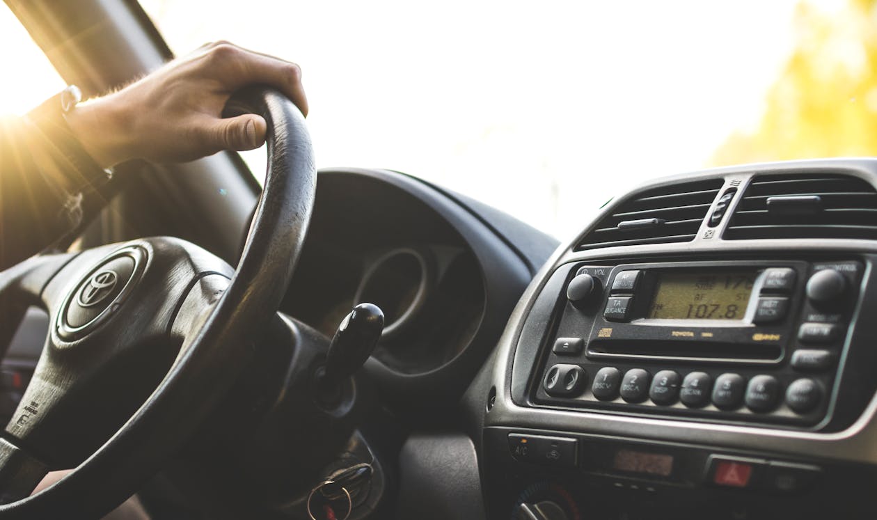 un homme conduit la main sur le volant pris en photo sur le coté passager