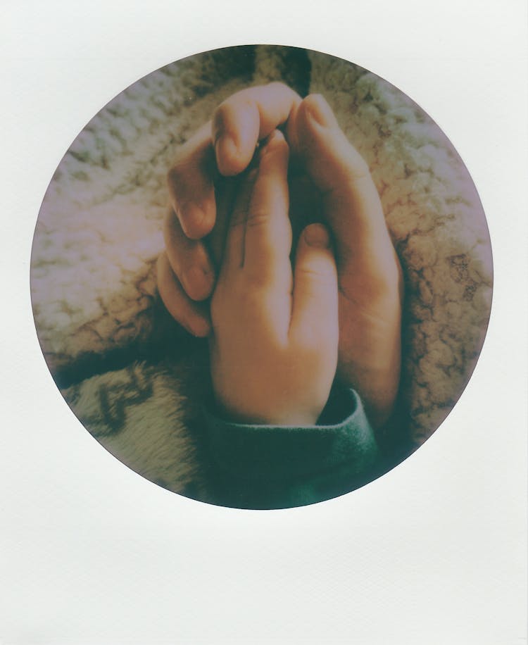 A Round Frame Polaroid Of A Parent And Child Holding Hands