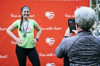 一名女子在完成“用心奔跑”马拉松比赛后，与奖牌合影