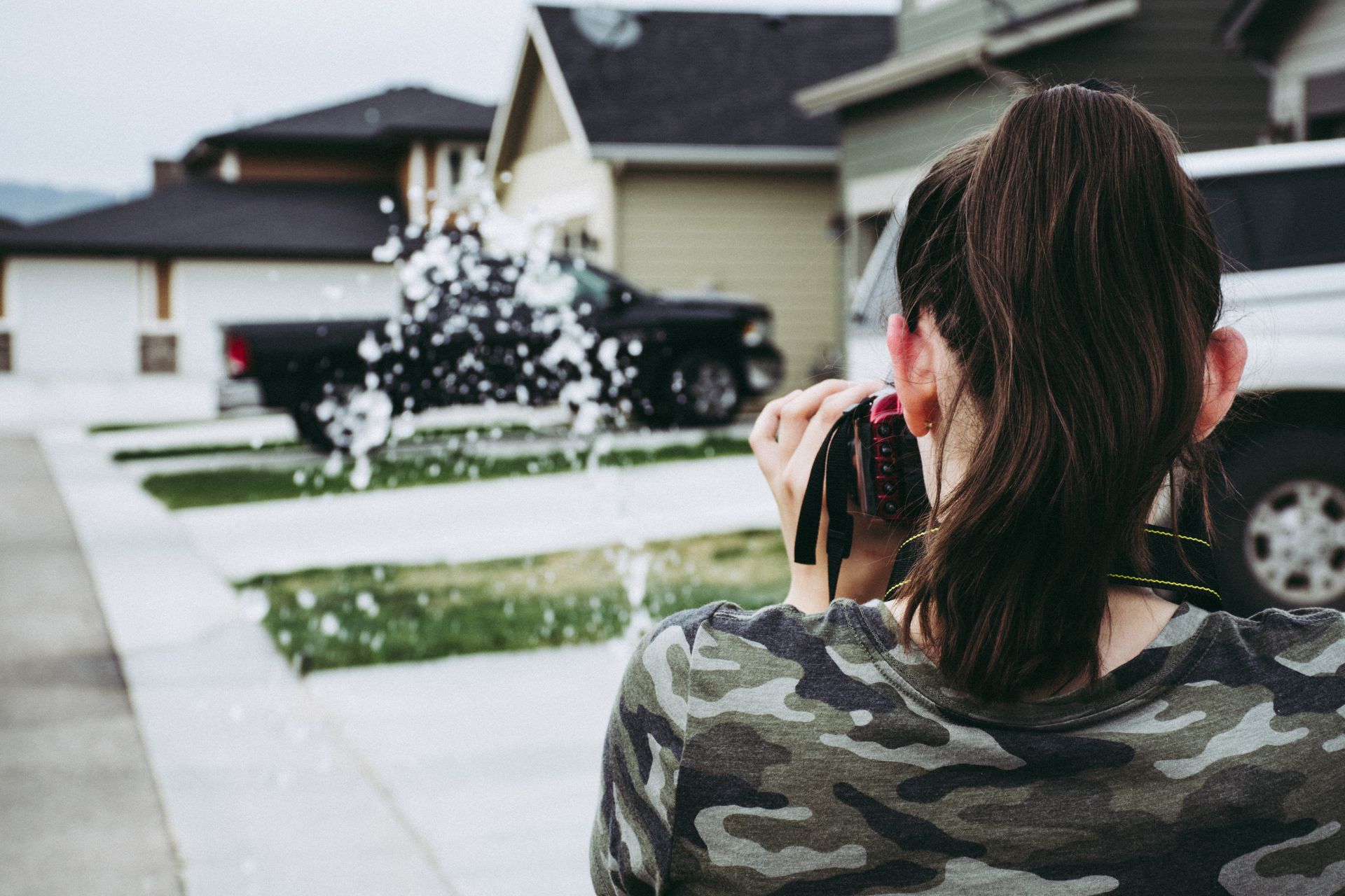 Young woman photographer focusing on urban street with camera in hand.