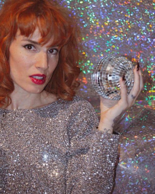 A Woman in Silver Dress Holding a Mirror Ball