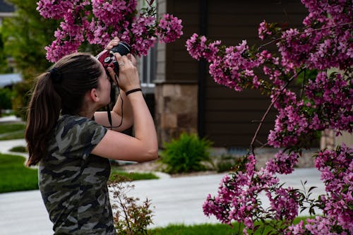 Mujer En Camisa De Camuflaje Gris Sosteniendo La Cámara