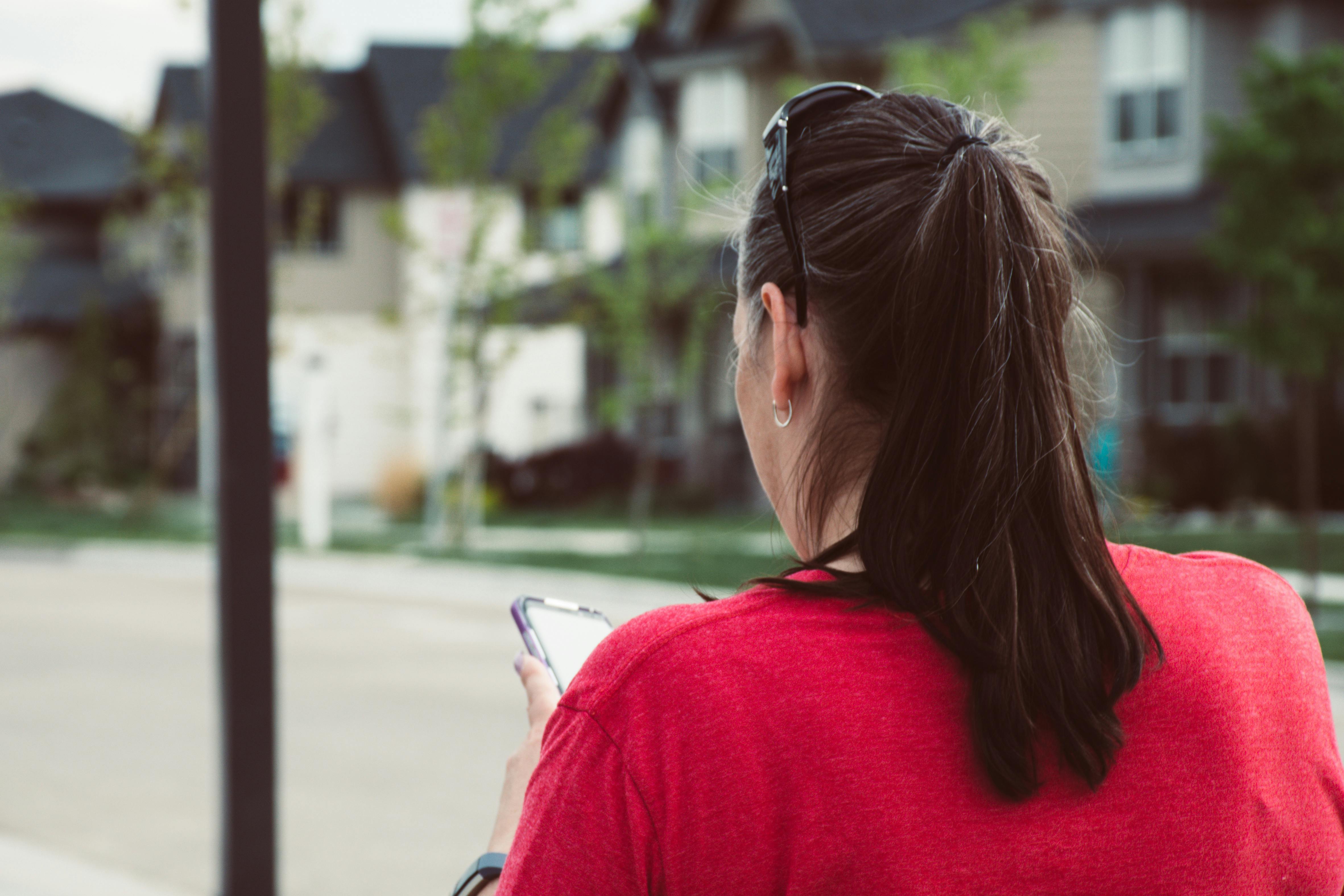 Casual urban scene of a woman using a smartphone outdoors in daylight.