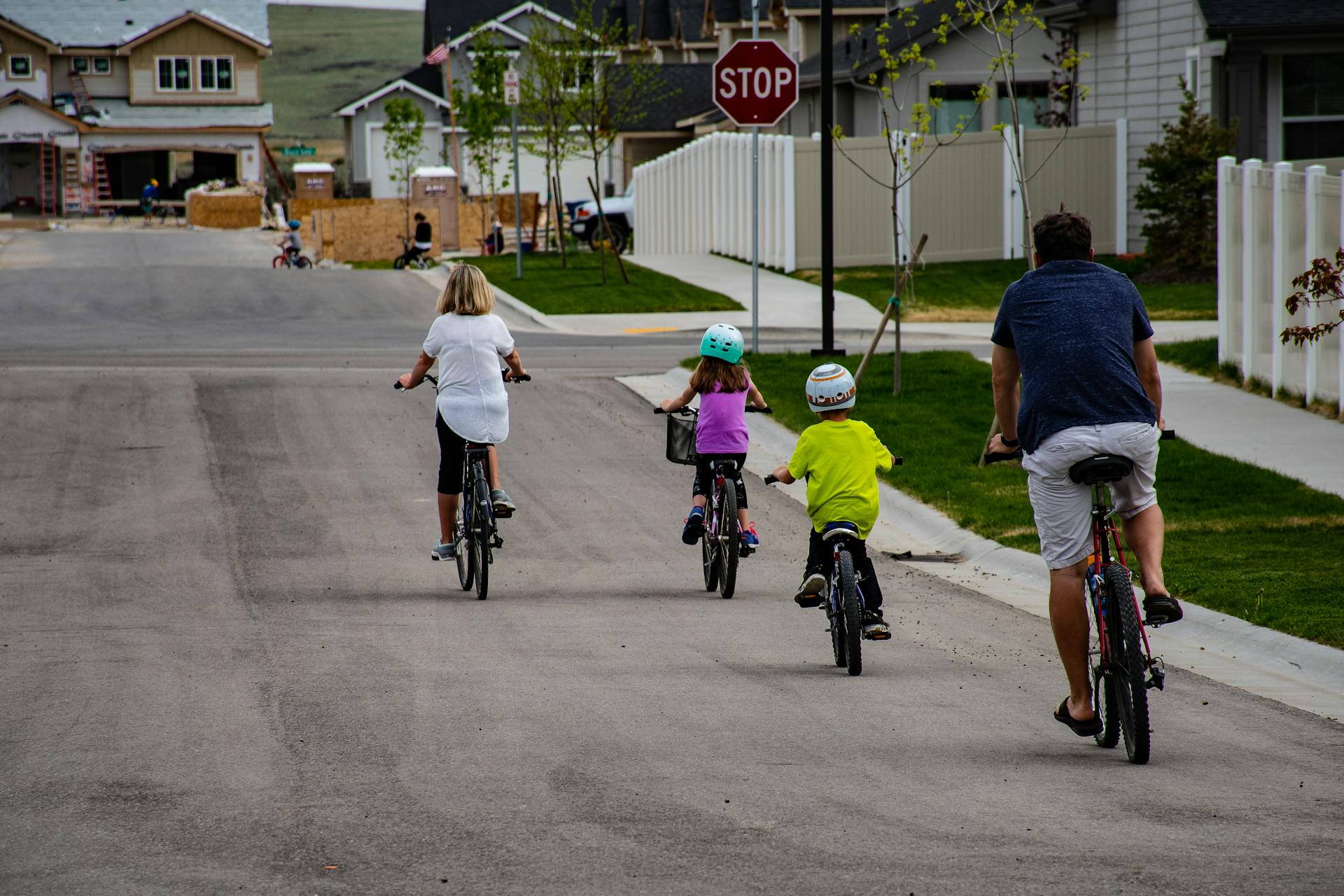 A family enjoys biking together on a suburban street, highlighting active outdoor lifestyle.