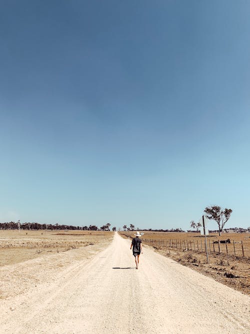 Free A Person Walking in the Rural Road Stock Photo