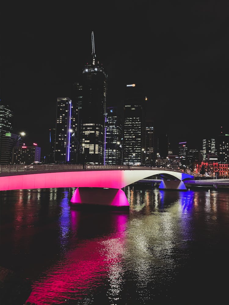 Black City With Skyscrapers At Night And Pink Illuminated Bridge