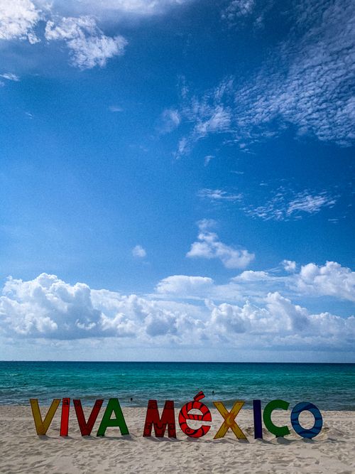 Free Colorful Viva México sign on a sandy beach with vibrant blue skies and clouds. Stock Photo