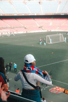 A passionate soccer fan with a team scarf watches a game in a large stadium.