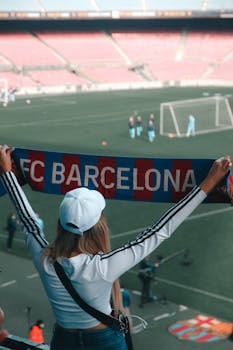 Excited FC Barcelona fan holding a team scarf at the stadium, enjoying a soccer match.
