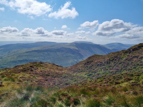 Free Serene view of lush green hills under blue skies in the UK. Perfect for nature lovers. Stock Photo