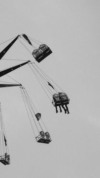Silhouette of people enjoying a thrilling swing ride at a carnival in black and white.