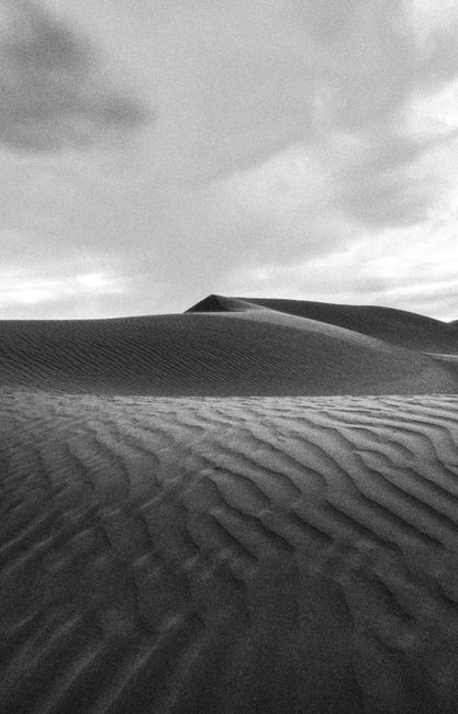 Black and white photograph capturing the serene beauty of sand dunes in the Algerian Sahara Desert.