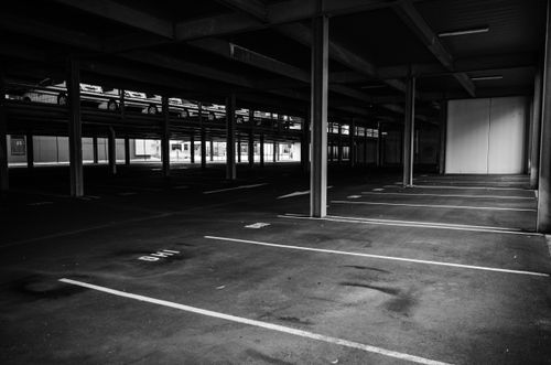 Free Grayscale image of an empty indoor parking lot with marked spaces and concrete posts. Stock Photo