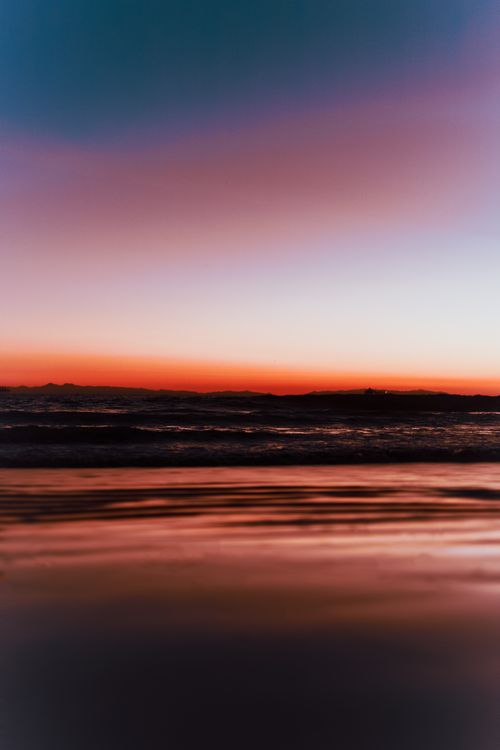 Free Tranquil seascape at sunset with vivid twilight colors over gentle waves. Perfect for peaceful ambiance. Stock Photo