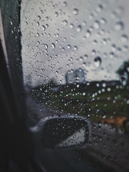 Close-up of raindrops on a car window with a blurred rainy view outside. Perfect for weather themes.