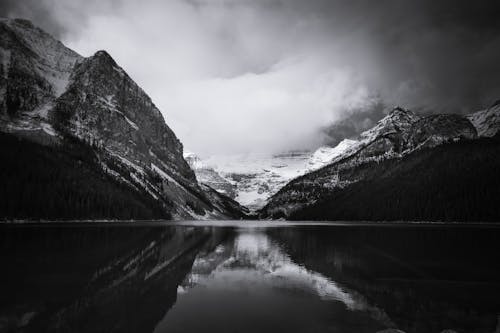 Grayscale Photo of Lake Near Mountains