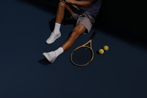 Free A Tennis Player Resting on the Ground Stock Photo