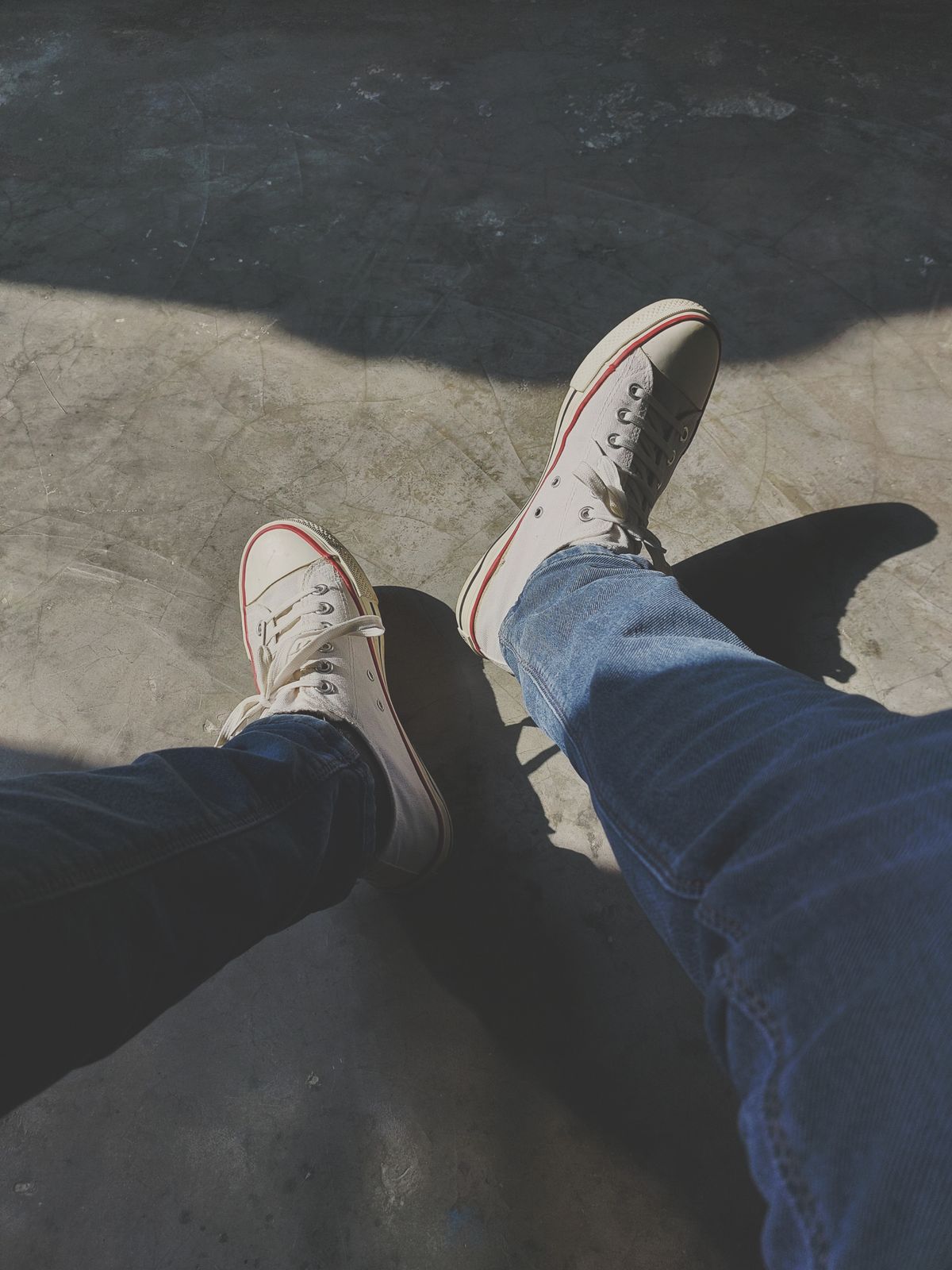 Person styled in white sneakers with blue jeans