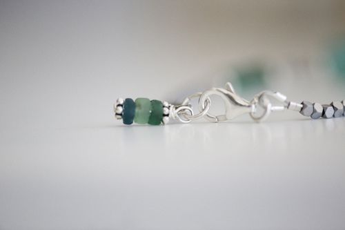 Free Detailed close-up of silver jewelry with blue and green beads on a white background. Stock Photo