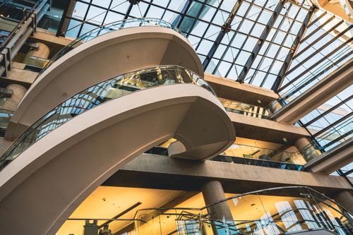 Free A modern interior showcasing curved staircases and expansive glass ceilings in an architectural setting. Stock Photo
