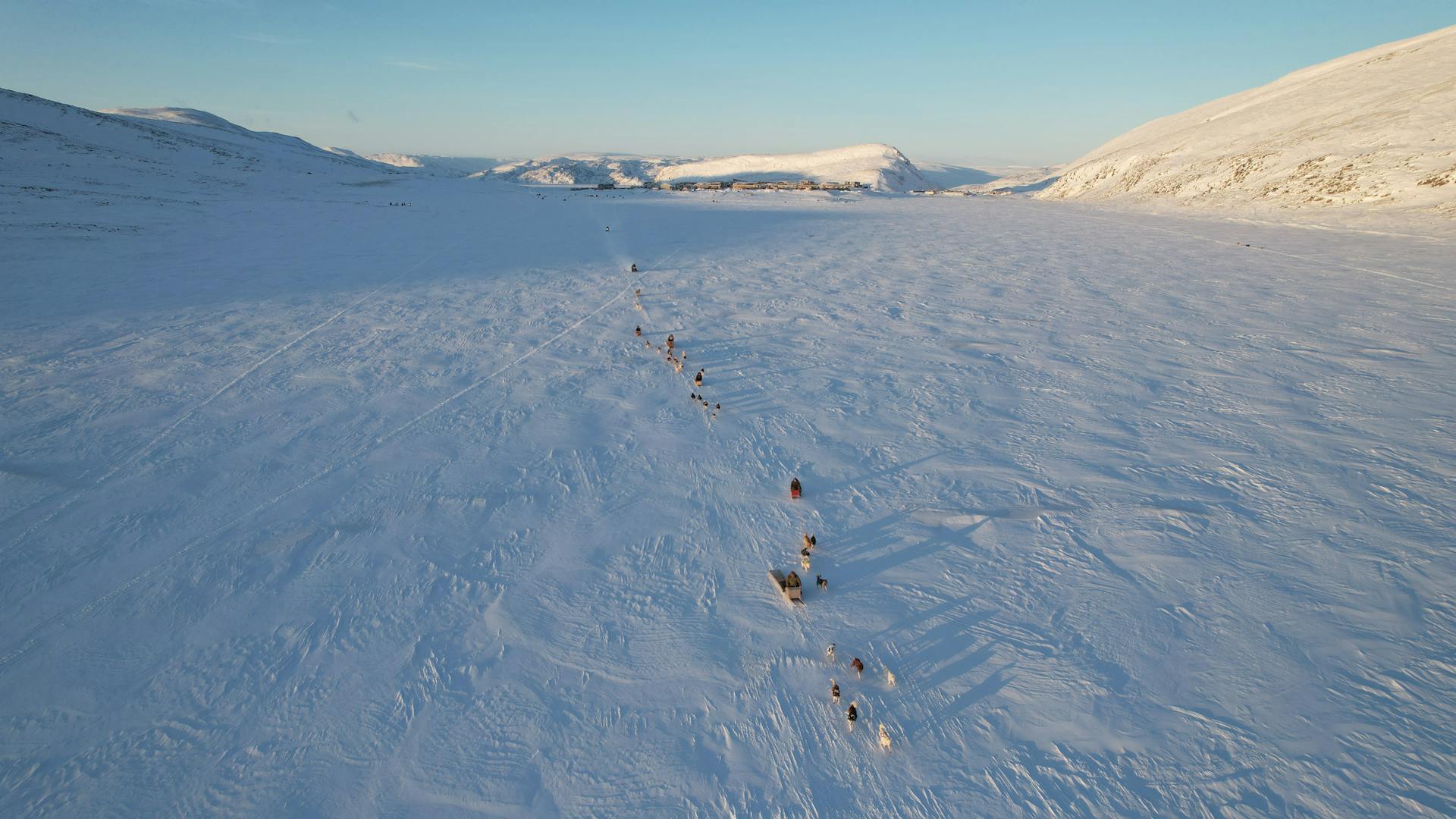 An Aerial Shot of Dogs Pulling Sleds on a Snow Covered Field