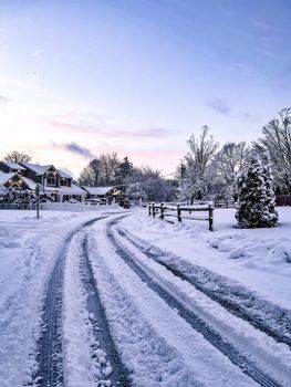 A serene snowy suburban neighborhood at dawn with snow-covered trees and road. Perfect for seasonal imagery.