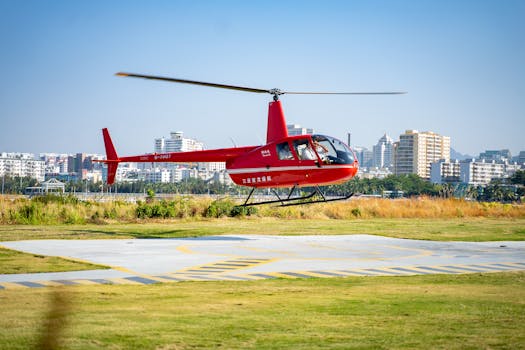 A vibrant red helicopter landing on an urban helipad amidst high-rise buildings.