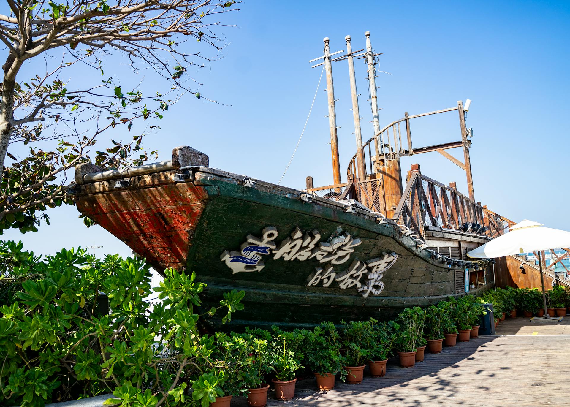 A picturesque vintage wooden ship surrounded by lush green plants on a sunny day.