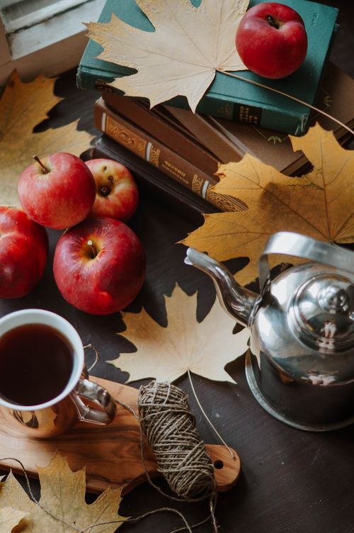 Free A warm still life featuring apples, a kettle, and tea amidst autumn leaves. Stock Photo