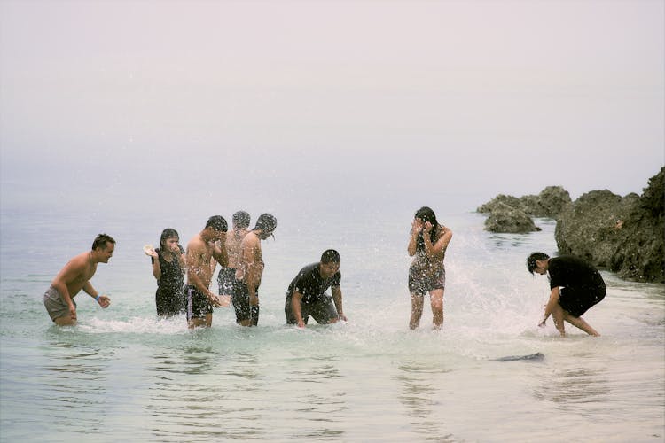 Group Of Friends Standing Having Fun Splashing On Sea Water