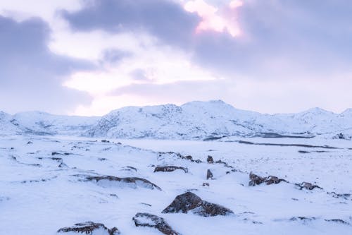 Snow-Covered Ground and Mountains during Sunrise