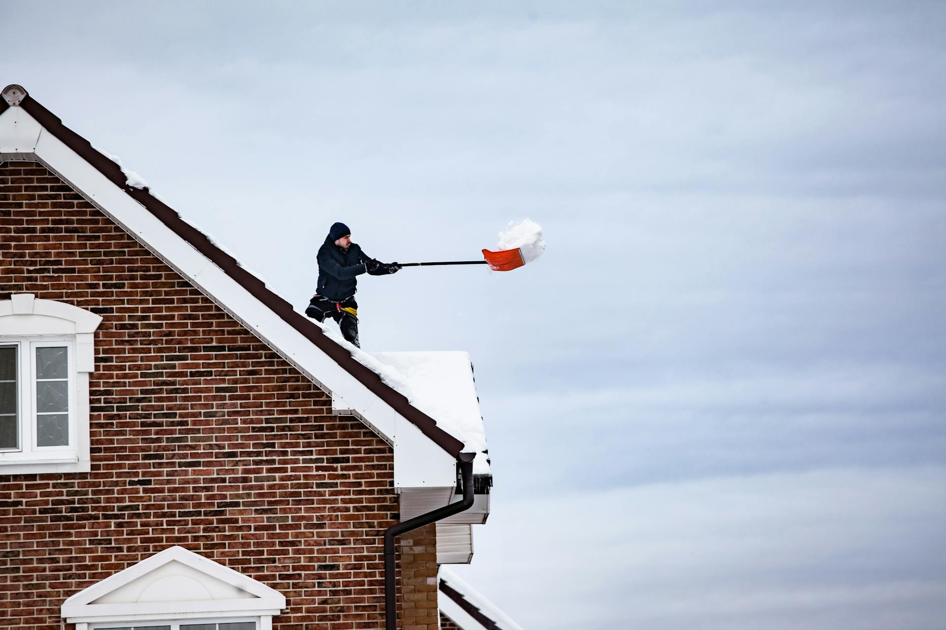 Man Clearing Snow from a House Roof