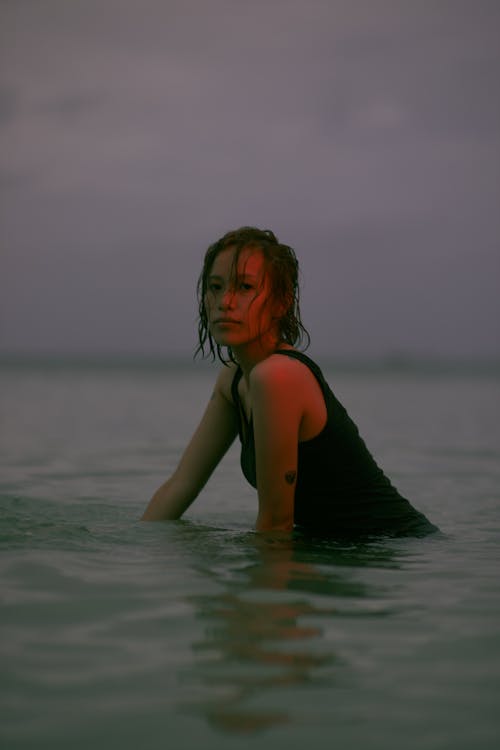 Woman Posing Wearing Black Tank Top Sitting on Sea Water