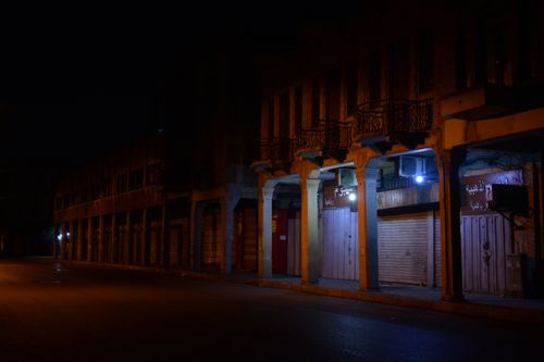 Free A quiet urban street with closed illuminated shops at night. Stock Photo