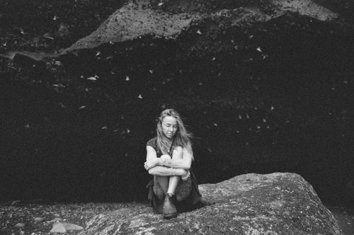 Free A serene black and white portrait of a woman sitting on a rock, captured outdoors in Bali. Stock Photo