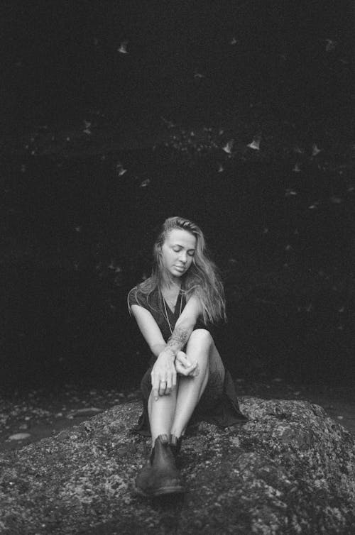 Black and White Portrait of Young Woman Sitting on a Rock