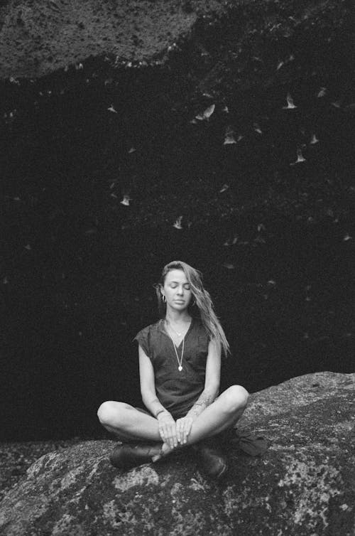 Black and White Portrait of a Woman Squatting on a Rock 