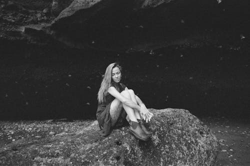 Free Black and White Portrait of a Woman Sitting on a Rock  Stock Photo