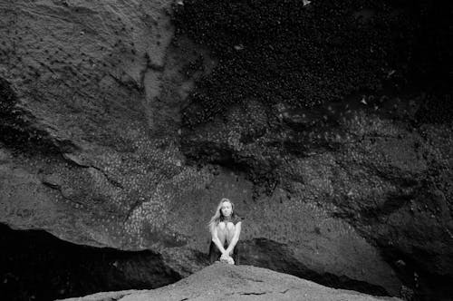 Black and White Portrait of a Woman Sitting on a Rock Formation