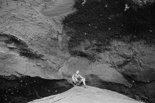 Free Grayscale Photo of Woman in Cave Sitting on a Rock  Stock Photo
