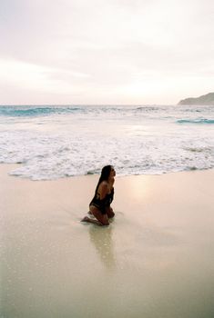 Capture the essence of tranquility with a woman relaxing on a Bali beach at sunrise.