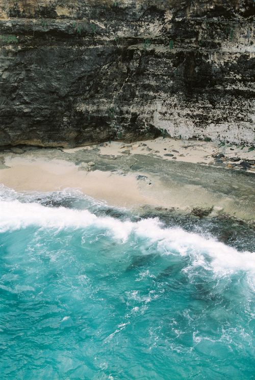 Free Breathtaking view of a secluded beach with turquoise waves crashing against rugged cliffs in Bali, Indonesia. Stock Photo