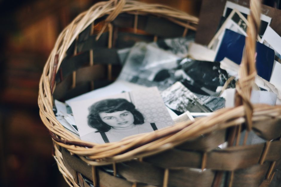 Como Praticar a Autocompaixão em Momentos Desafiadores 2 A collection of vintage black and white photos in a woven basket evokes nostalgia.