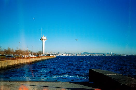 A vibrant seascape in Istanbul showcasing a radar tower and the city skyline under a clear blue sky.