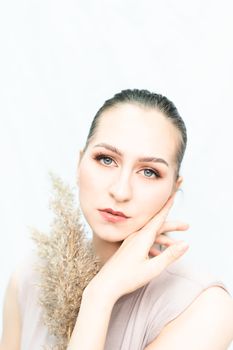 A serene portrait of a woman holding pampas grass against a white background, embodying elegance and style.