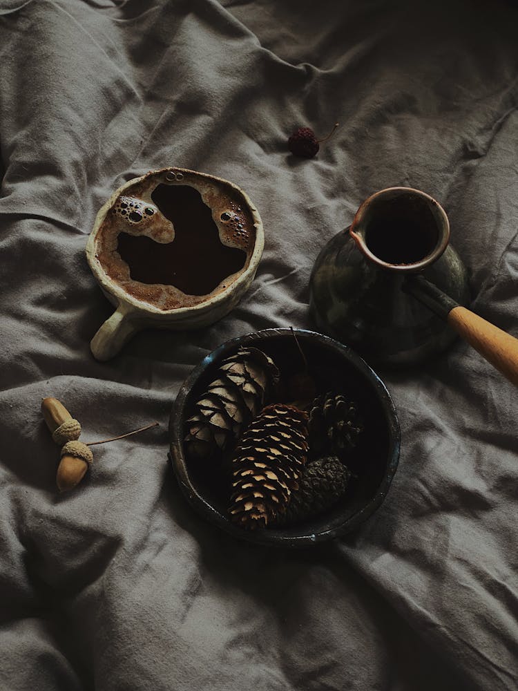 A Bowl With Pine Cones And A Cup Of Drink