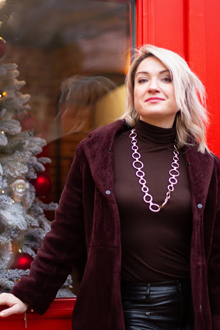 A Woman Wearing A Velvet Coat And A Necklace