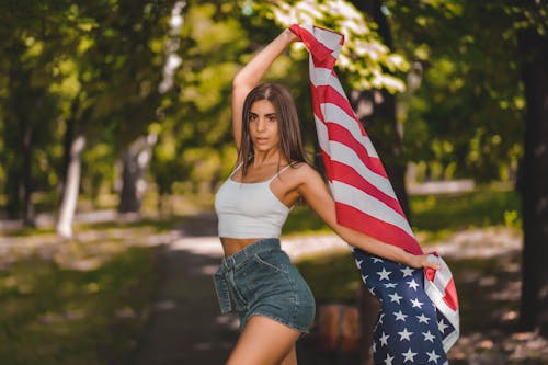 A Woman in White Crop Top Holding a Flag of USA