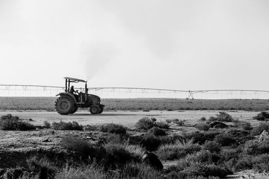 Black and white image of a tractor on a Qatari farm with irrigation system.